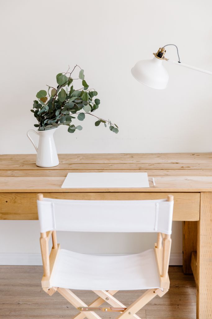 Minimalist wooden desk with eucalyptus and white decor for a calming workspace.